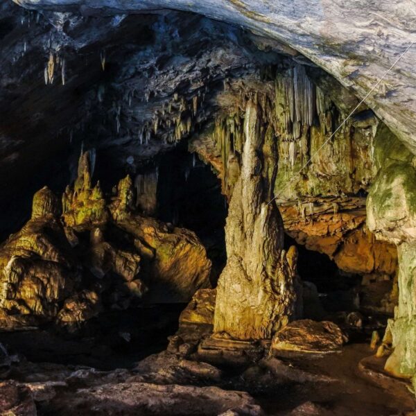 stalagmite and a stalactite in a dark limestone cave, with a gentle light source highlighting their unique textures.