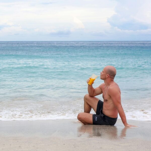 a man enjoying a drink on a beach